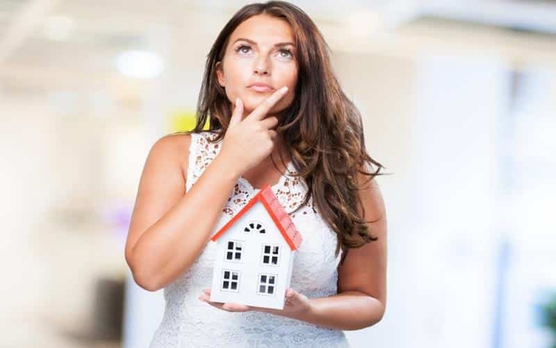 Woman holding a house and thinking about something